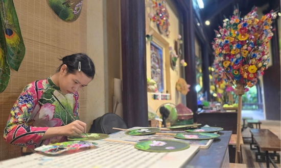 An artisan paints lotus-leaf fans right at a heritage site